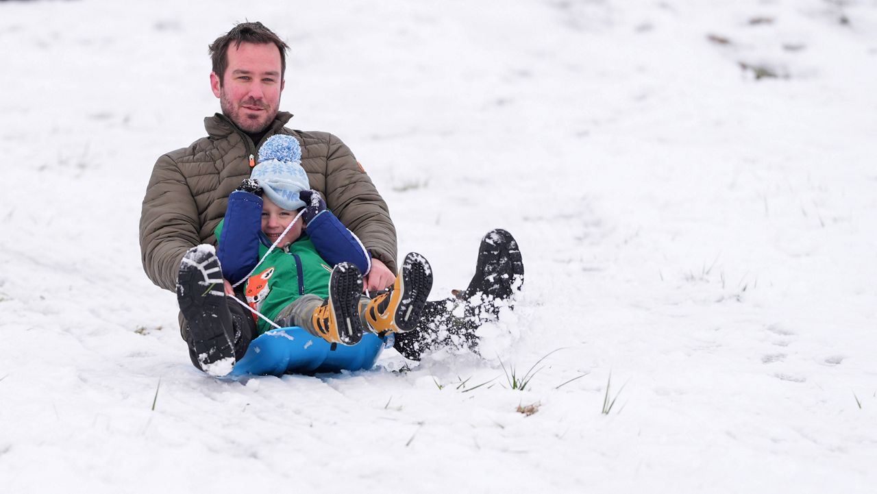 Nate Miller sleds down a hill with his son Henry, Saturday, Jan. 11, 2025, in Nashville, Tenn. (AP Photo/George Walker IV)