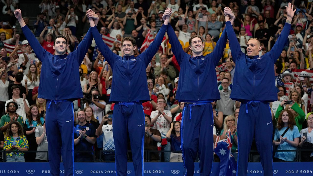 The United States men's 4x100-meter freestyle relay team celebrates on the podium after winning the gold medal at the 2024 Summer Olympics, Saturday, July 27, 2024, in Nanterre, France. (AP Photo/Matthias Schrader)