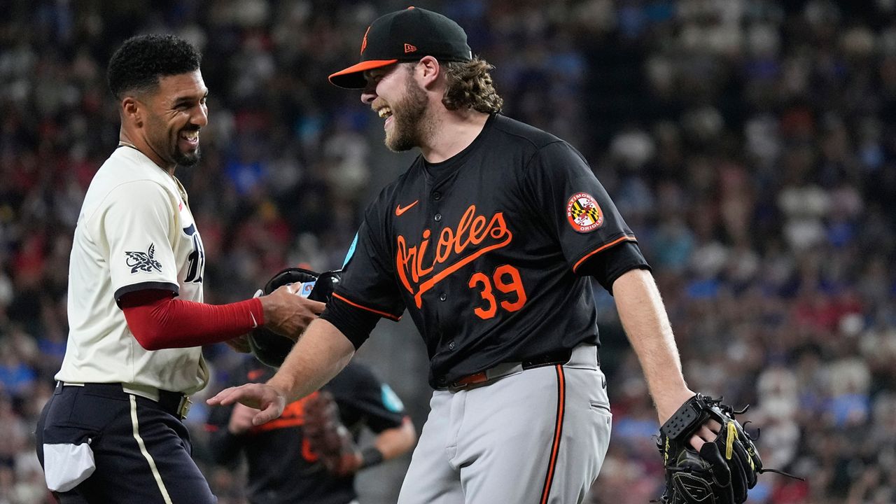 Baltimore Orioles starting pitcher Corbin Burnes (39) laughs with Texas Rangers baserunner Marcus Semien, left, after out three to end the third inning of a baseball game in Arlington, Texas, Friday, July 19, 2024. (AP Photo/LM Otero)