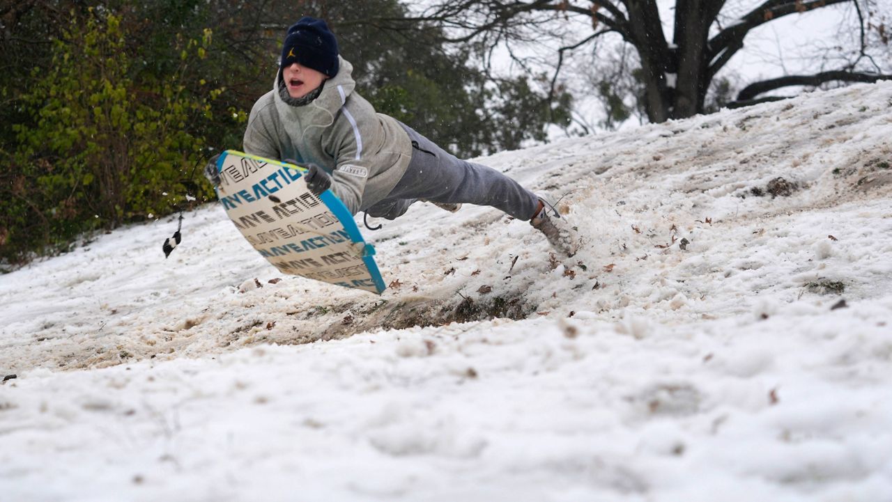 Luke Choat slides on a small snow covered hill Thursday, Jan. 9, 2025, in Richardson, Texas. (AP Photo/LM Otero)