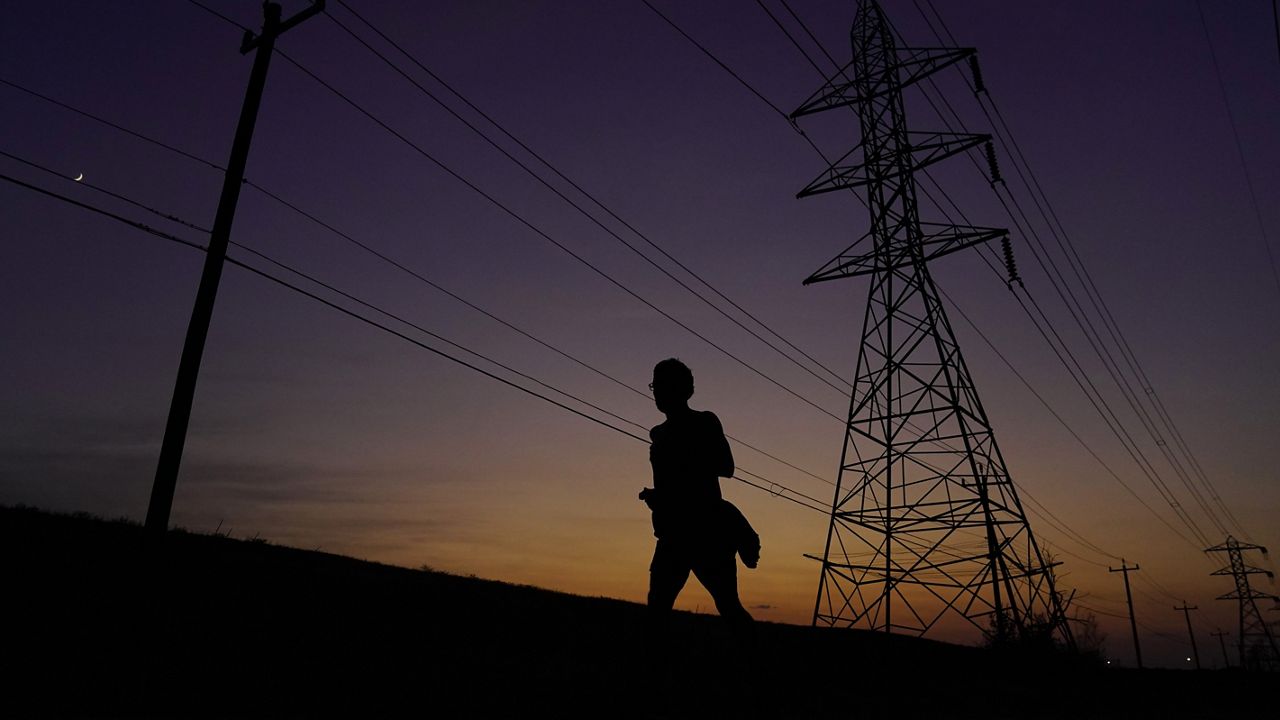 A jogger passes power lines during a sunset run, Aug. 20, 2023, in San Antonio, as high temperatures continue to stress the power grid. (AP Photo/Eric Gay)