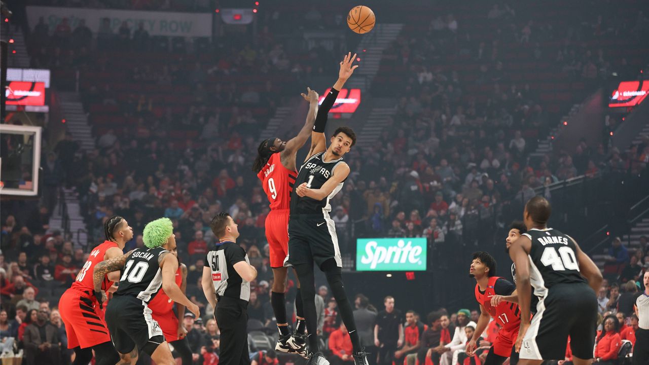 Portland Trail Blazers forward Jerami Grant (9) and San Antonio Spurs center Victor Wembanyama (1) jump up for the tipoff during the first half of an NBA basketball game Friday, Dec. 13, 2024, in Portland, Ore. (AP Photo/Amanda Loman)