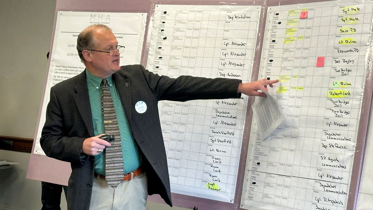 Sgt. Aaron Skolfield of the Sagadahoc County Sheriff's Office points to poster boards with information about the Lewiston shooting investigation during a State House press conference. (Spectrum News/Susan Cover)