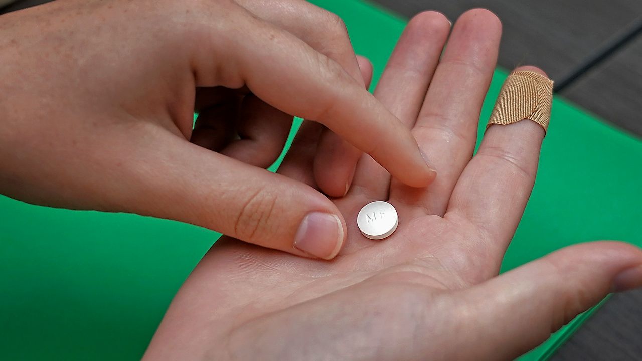 A patient prepares to take the first of two combination pills, mifepristone, for a medication abortion during a visit to a clinic in Kansas City, Kan., on, Oct. 12, 2022. (AP Photo/Charlie Riedel, File)