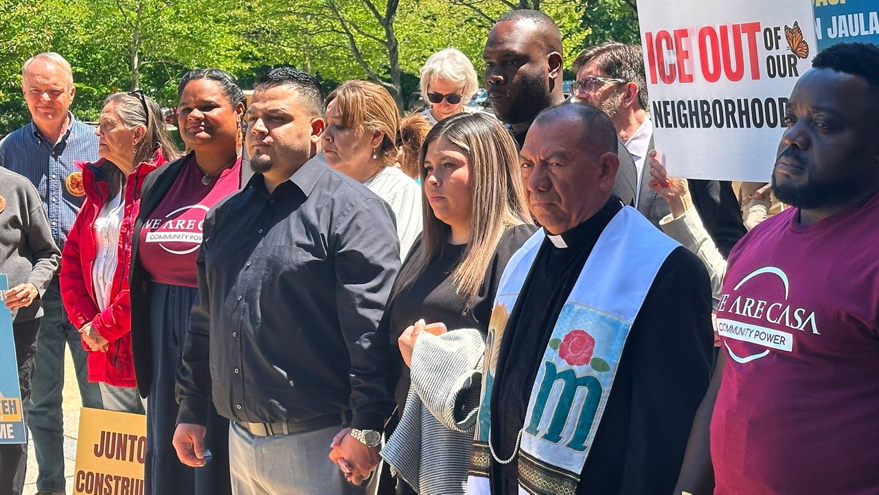 Kilmar Abrego Garcia and his wife, center, hold hands as people rally in support of him at a news conference outside federal court after a hearing in his case on Tuesday, May 12, 2026, in Greenbelt, Md. (AP Photo/Michael Kunzelman)
