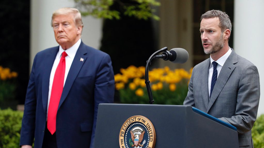 President Donald Trump listens as Adam Boehler, then-CEO of U.S. International Development Finance Corporation, speaks about the coronavirus in the Rose Garden of the White House, Tuesday, April 14, 2020, in Washington. (AP Photo/Alex Brandon, File)