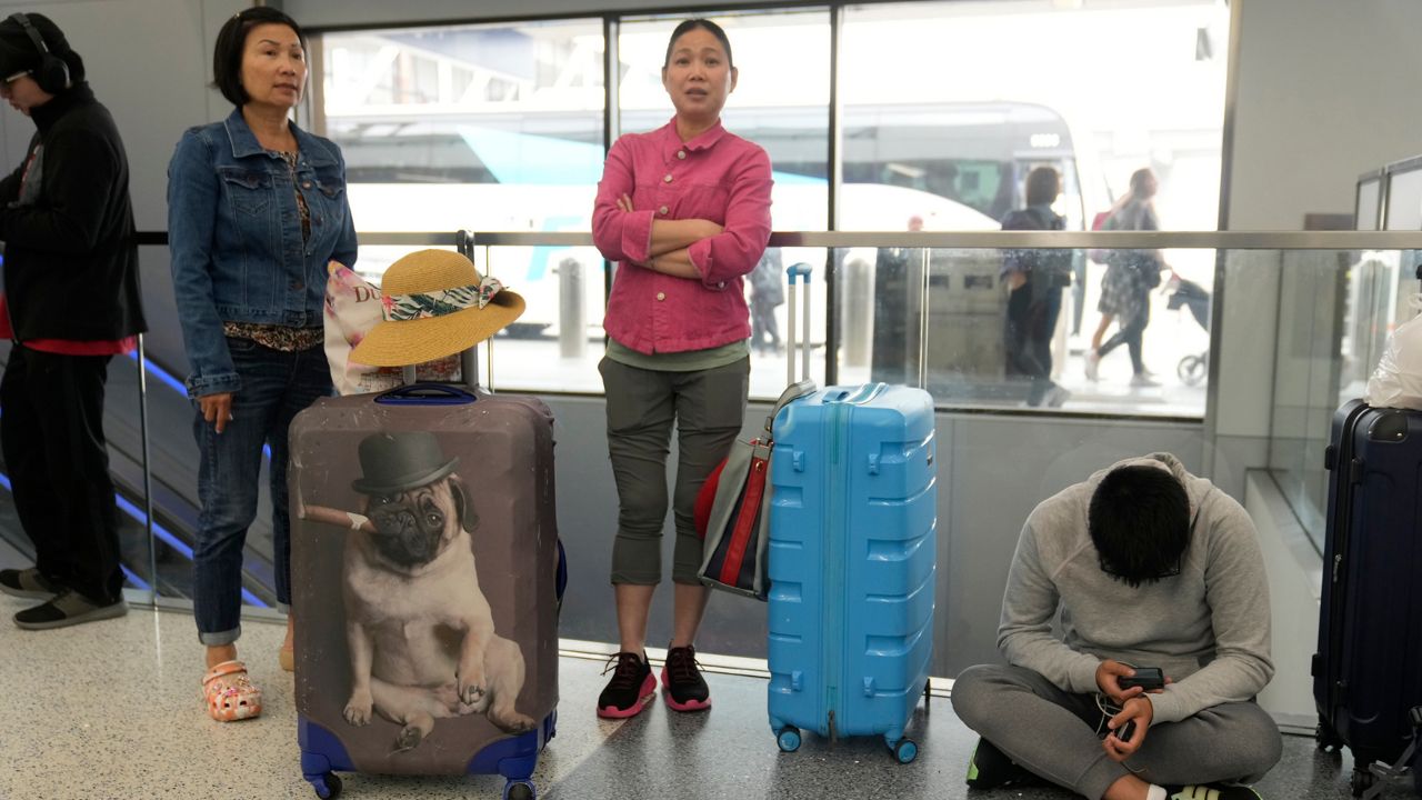 Travelers from Hong Kong wait for travel options after their vacation flight to Cancun, Mexico, was suddenly cancelled disrupting their planned vacation at the United Airlines terminal at Los Angeles International airport, Wednesday June 28, 2023, in Los Angeles. (AP Photo/Damian Dovarganes)