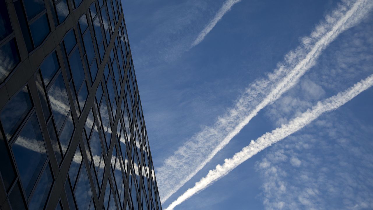 In this Jan. 23, 2015 file photo, airplane contrails are reflected in a building as they cross the early morning sky above Pennsylvania Ave. in Washington. The United Nations' aviation arm has ratified an agreement to control global warming emissions from international airline flights. It is the first climate-change pact to set limits on a single, global industry.