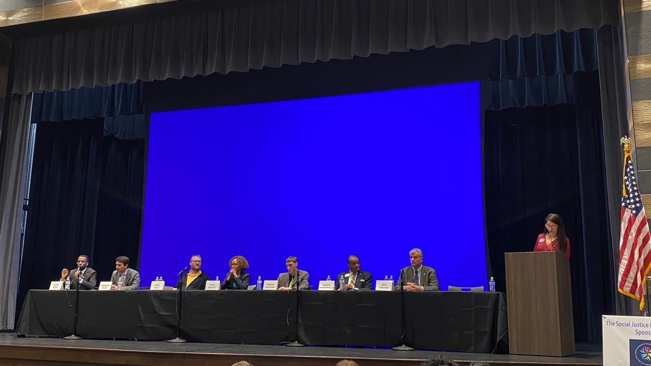 Akron mayoral candidates at a social justice forum, (from left) Mark Greer, Shammas Malik, Keith Mills, Tara Mosley, Joshua Schaffer, Marco Sommerville and Jeff Wilhite, with forum moderator Cynthia Peeples and Akron NAACP President Judi Hill. (Spectrum News 1/Jennifer Conn)