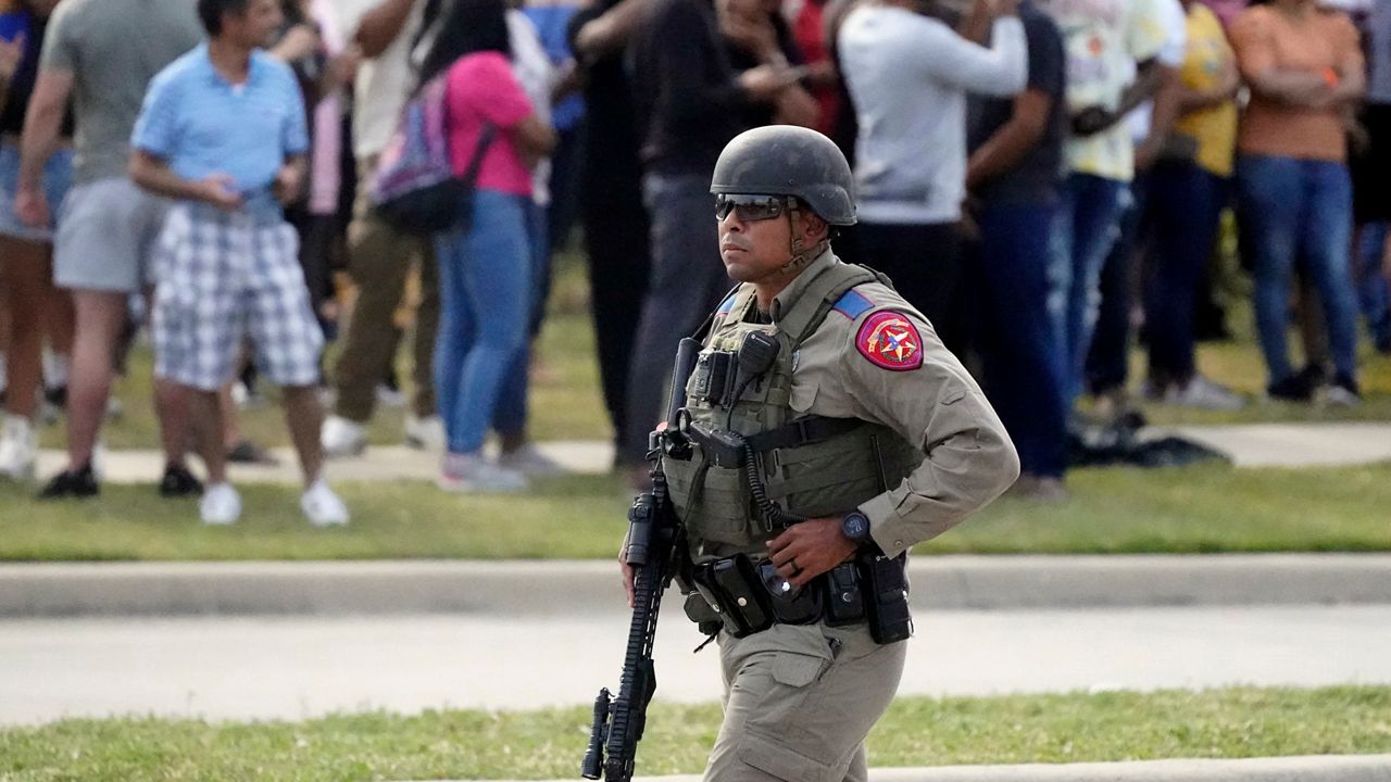 A law enforcement officer walks as people are evacuated from a shopping center where a shooting occurred Saturday, May 6, 2023, in Allen, Texas. (AP Photo/LM Otero)