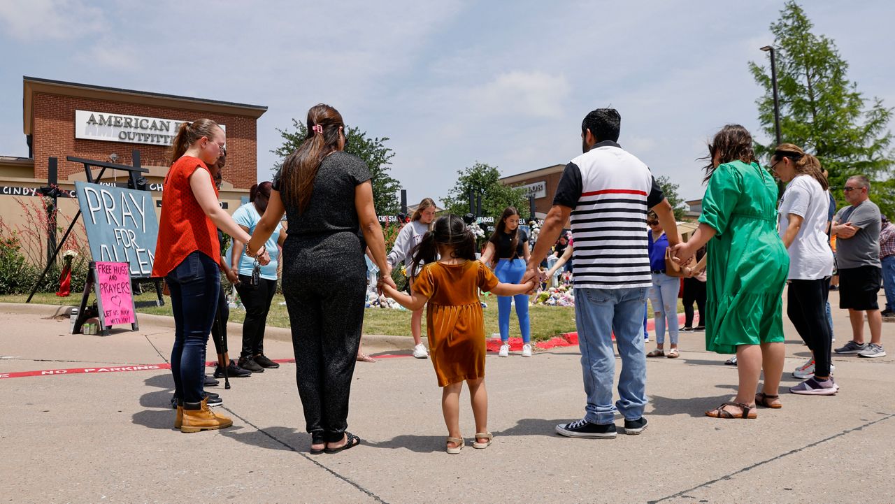 People hold hands as they pray at a memorial for victims of the Allen Premium Outlets mass shooting, May 9, 2023, in Allen, Texas. Misleading claims about the gunman who killed eight people at a Dallas-area shopping center are swirling on Twitter, thanks in part to the platform's owner, Elon Musk. Musk has questioned the gunman's self-professed white supremacist views, and said they could be part of a “psychological operation” to mislead the public. (Elías Valverde II/The Dallas Morning News via AP)