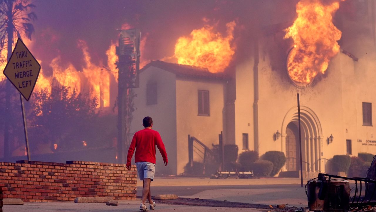FILE - A man walks in front of the burning Altadena Community Church, Wednesday, Jan. 8, 2025, in the downtown Altadena section of Pasadena, Calif. (AP Photo/Chris Pizzello, File)