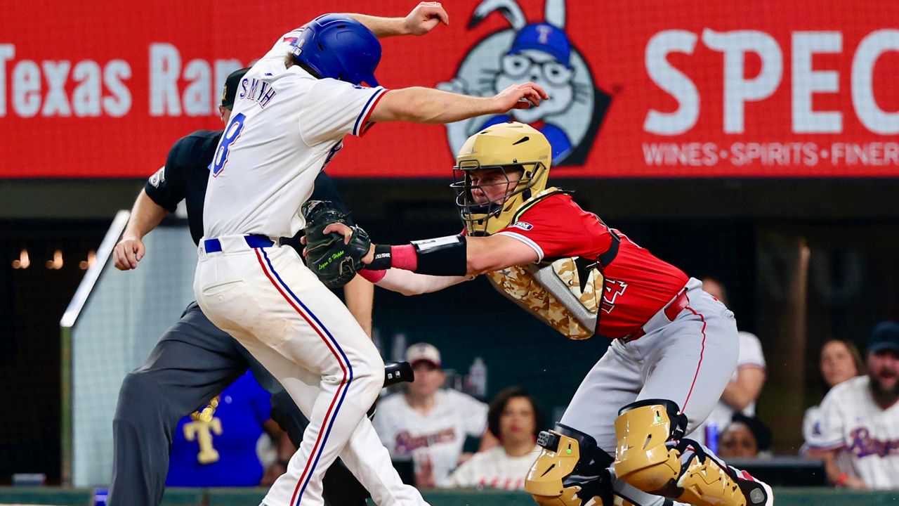 Texas Rangers' Josh Smith (8) is tagged out at the plate by Los Angeles Angels catcher Logan O'Hoppe (14) in the tenth inning of a baseball game Saturday, May 18, 2024, in Arlington, Texas. (AP Photo/Richard W. Rodriguez)