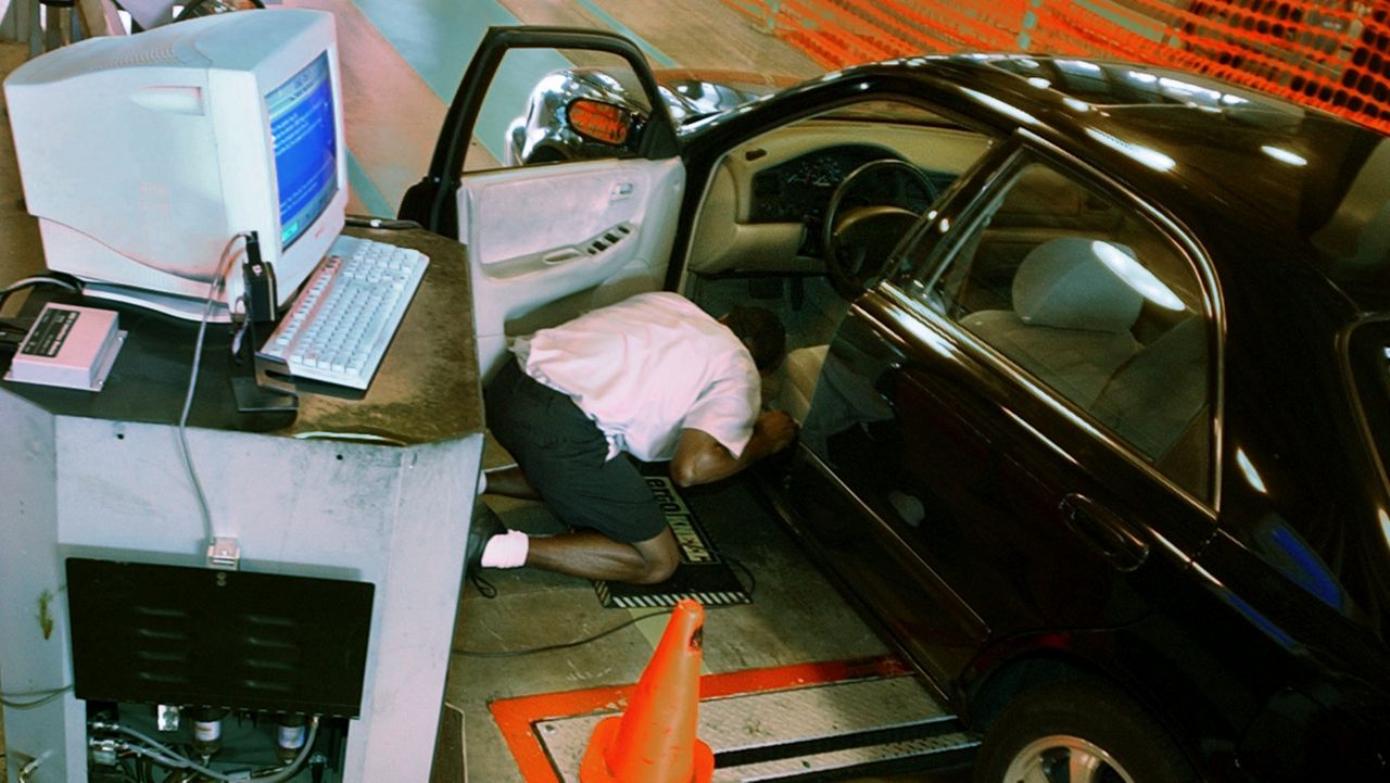 A New Jersey auto inspection employee connects a cord from the computer to an on-board-diganostic (OBD) computer under the dashboard of a car at the inspection station in Lawrence Township. N.J., Monday, Aug. 4, 2003. (AP Photo/Daniel Hulshizer)