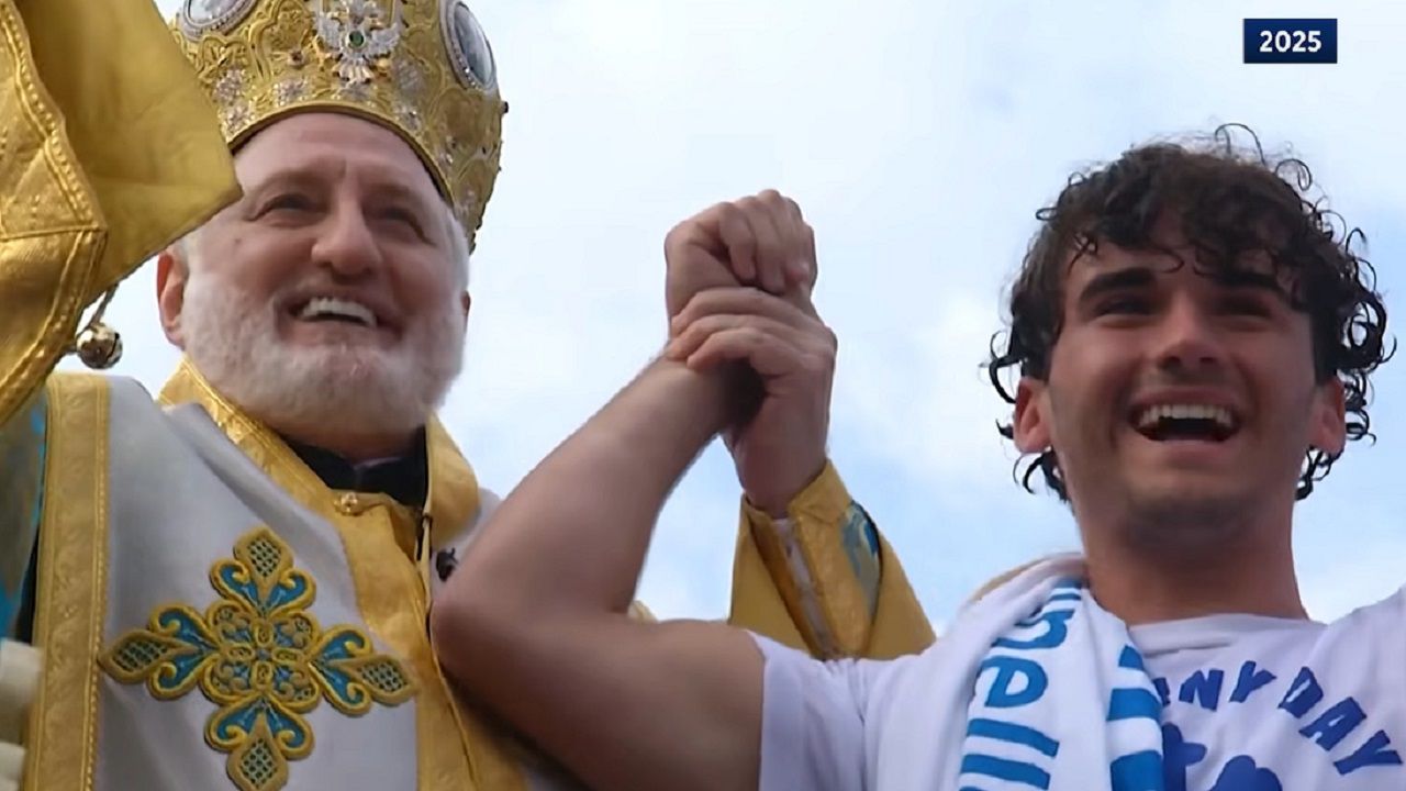 2025 cross retriever Luc Boillot celebrates with the Archbishop after emerging from the Spring bayou waters with the cross. (Spectrum News image)