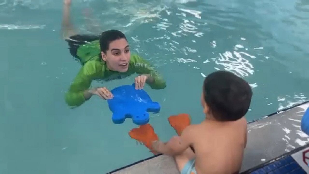 Swim instructor Madison Munoz works with Adrian at Watermelon Swim in Tampa. (Spectrum News image)