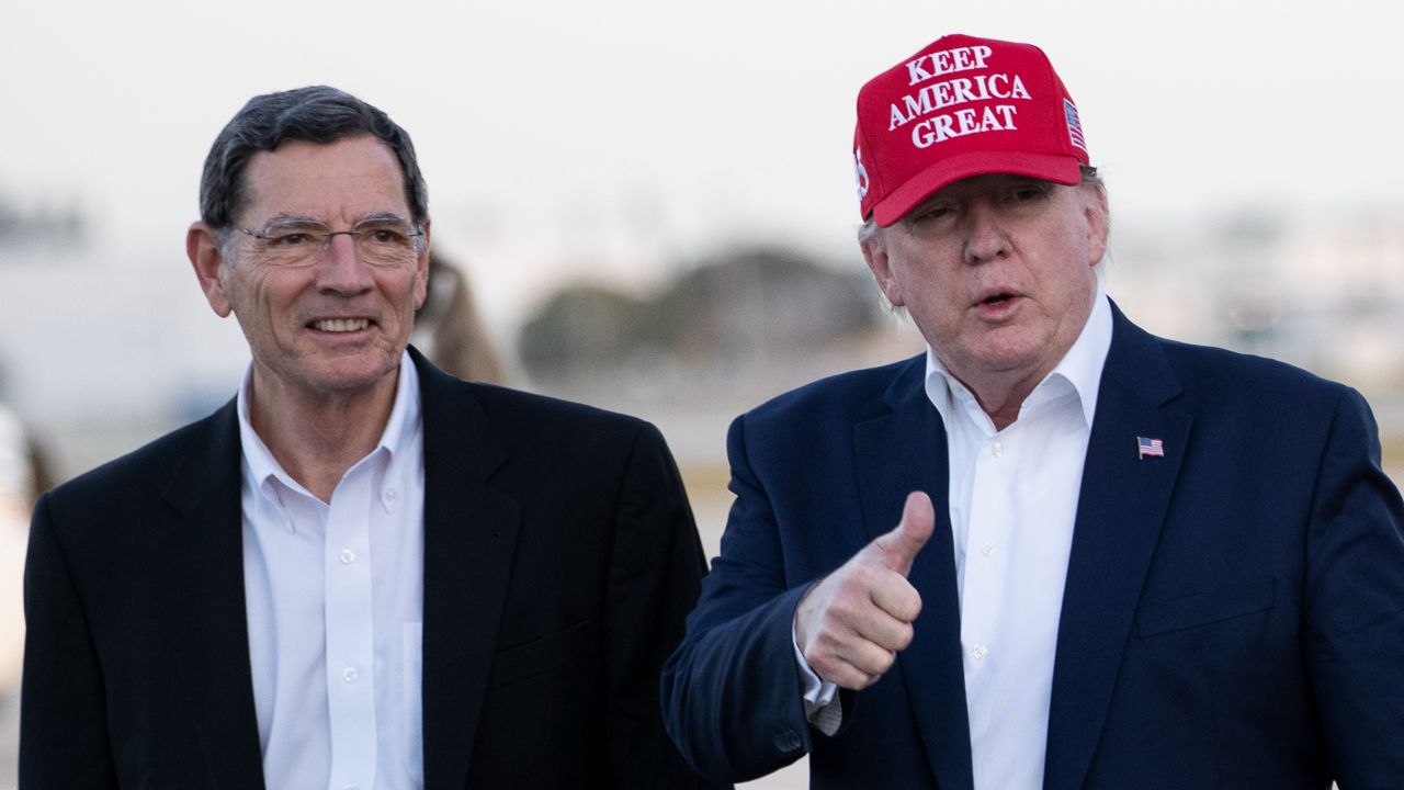 Then-President Donald Trump gives thumbs up as he steps off Air Force One, accompanied by Sen. John Barrasso, R-Wyo., at the Palm Beach International Airport, Friday, Nov. 29, 2019, in West Palm Beach, Fla. (AP Photo/Alex Brandon)