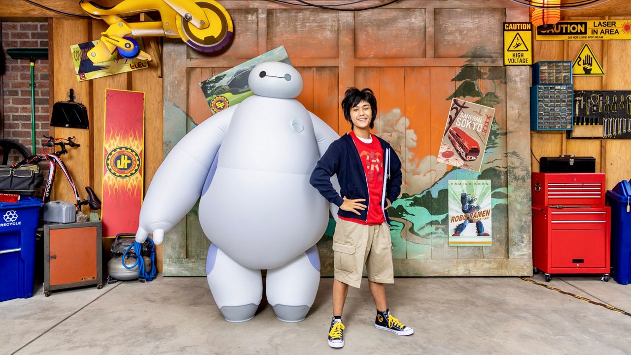 Boy genius Hiro Hamada and his huggable healthcare companion robot, Baymax, outside the Hamada Bot Shop. (Christian Thompson/Disneyland Resort)