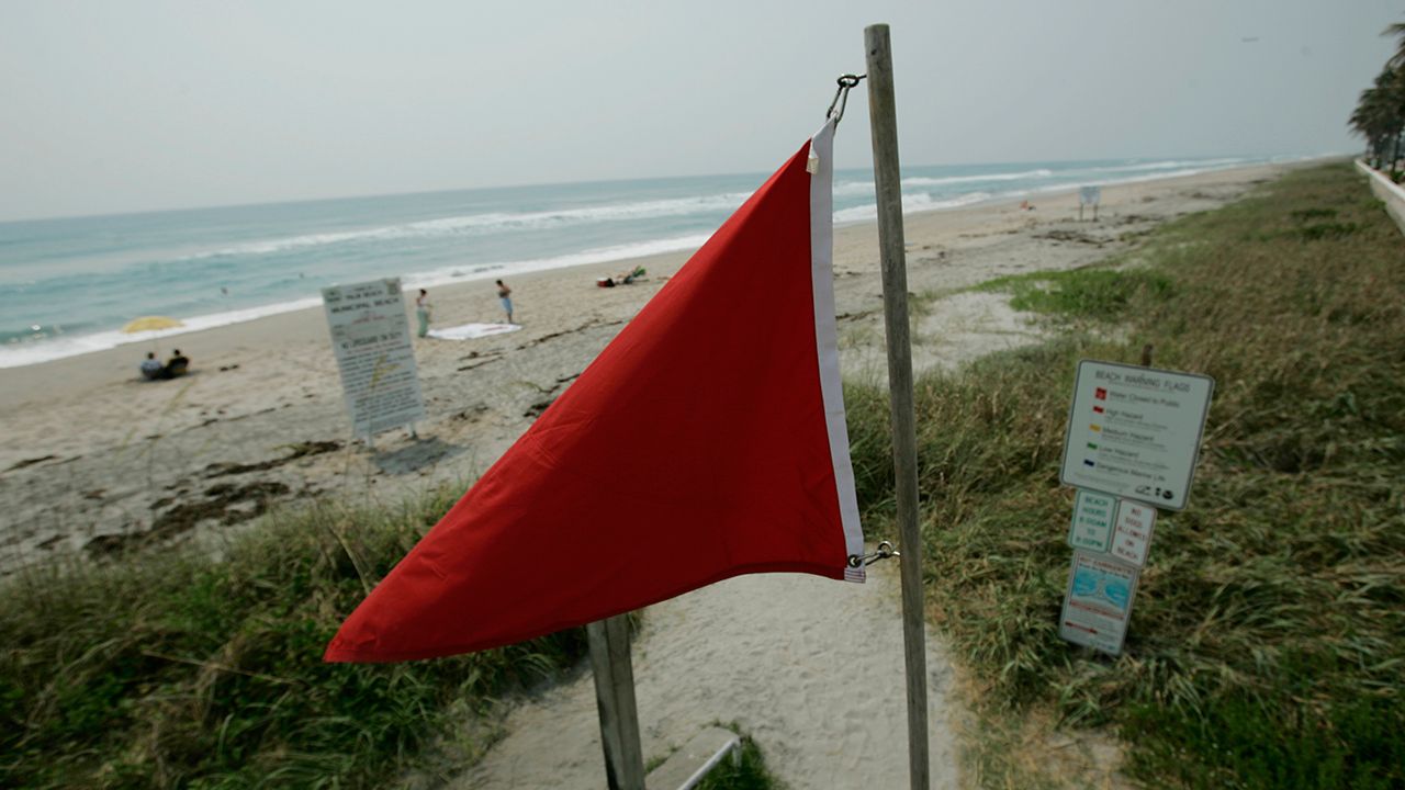Sign warns beachgoers of the risk of rip currents in the area. (Spectrum News)