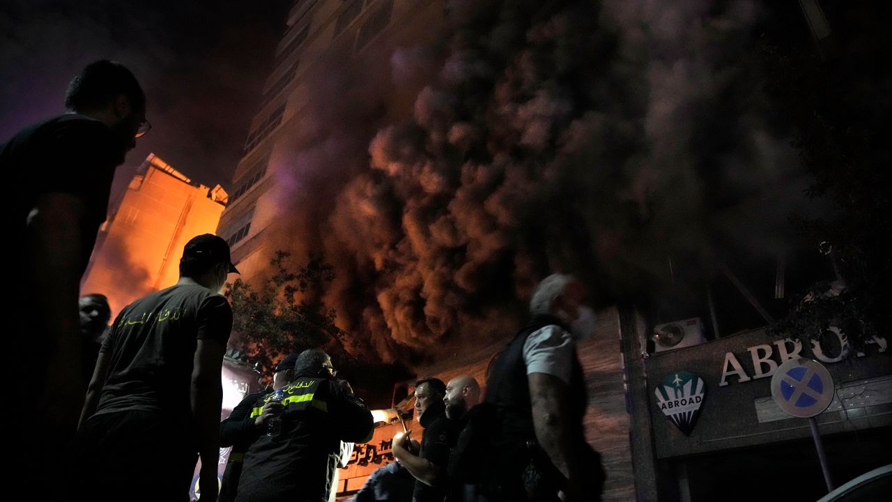 Firefighters and rescuers gather outside a computer shop hit in an Israeli airstrike in central Beirut, Sunday, Nov. 17, 2024. (AP Photo/Bilal Hussein)