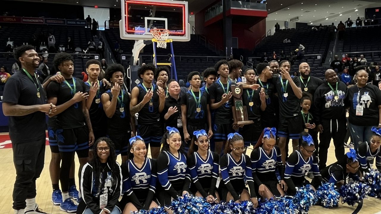 The Richmond Heights High School boys basketball team and cheerleaders stand with the Division IV state championship trophy after the OHSAA Boys State Tournament final at UD Arena on Sunday. (Spectrum News 1/Jacob Benge)