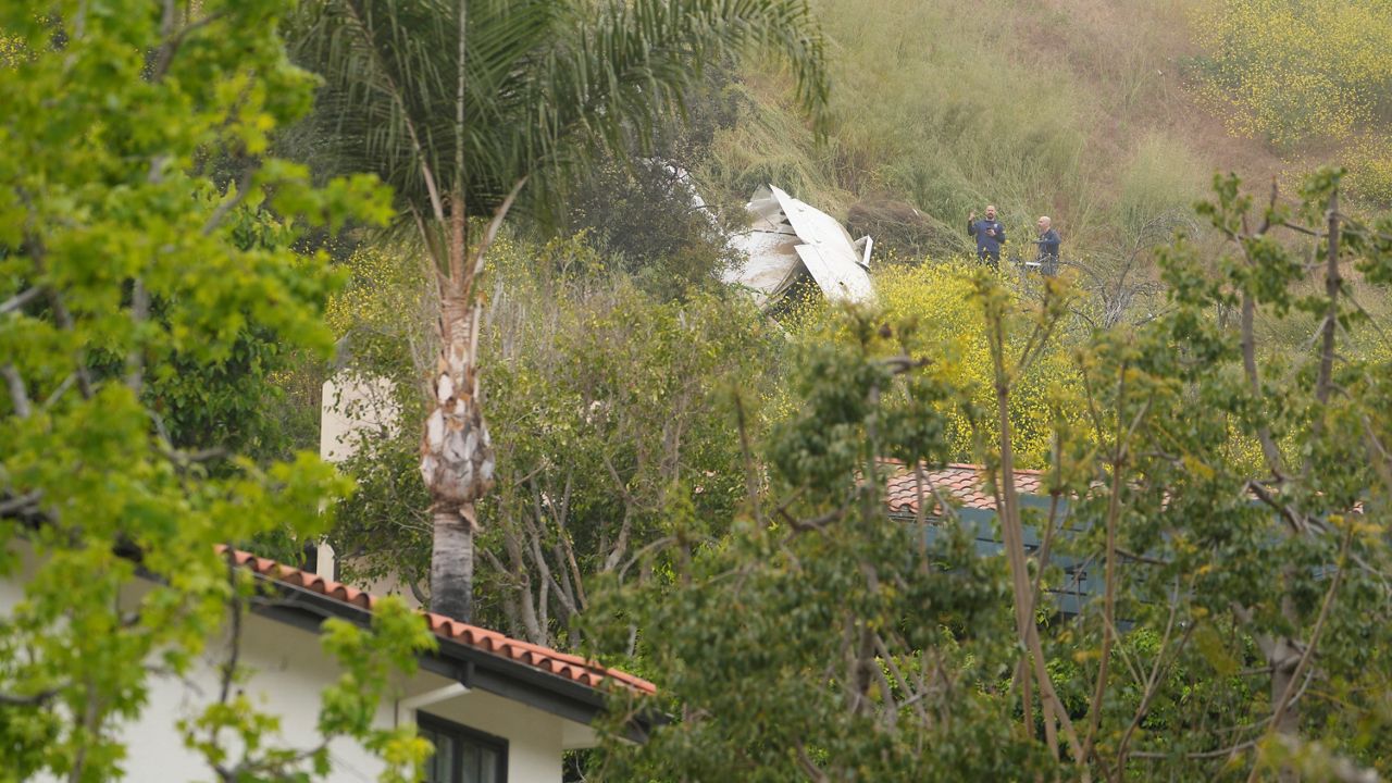 National Transportation Safety Board investigators inspect a downed plane on a steep hill above a home on Beverly Glen Circle in Los Angeles, Sunday, April 30, 2023. (AP Photo/Damian Dovarganes)