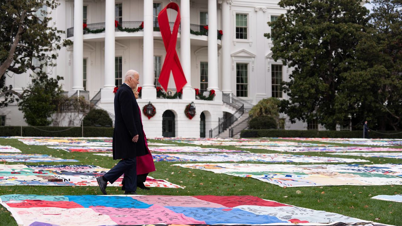 President Joe Biden, left, and first lady Jill Biden walk between AIDS Memorial Quilts spread over the South Lawn at the White House during a ceremony to commemorate World AIDS Day with survivors, their families and advocates, Sunday, Dec. 1, 2024, in Washington. (AP Photo/Manuel Balce Ceneta)