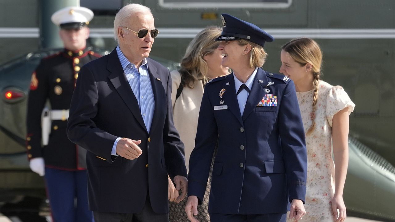 President Joe Biden is escorted by Air Force Col. Angela Ochoa, Commander, 89th Airlift Wing, as he arrives at Andrews Air Force Base, Md., Wednesday, June 12, 2024. Biden is headed to Italy for the G7 summit. Biden's granddaughter, Finnegan Biden, walks right. (AP Photo/Alex Brandon)