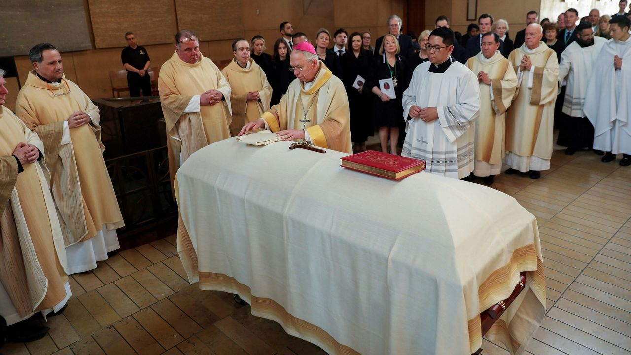 Archbishop Jose Gomez places Christian symbols; The Book of Gospels, a Cross and Miter, on the casket of Bishop David O'Connell during a funeral Mass at the Cathedral of Our Lady of the Angels in Los Angeles, Friday, March 3, 2023. (Jay L. Clendenin/Los Angeles Times via AP, Pool)