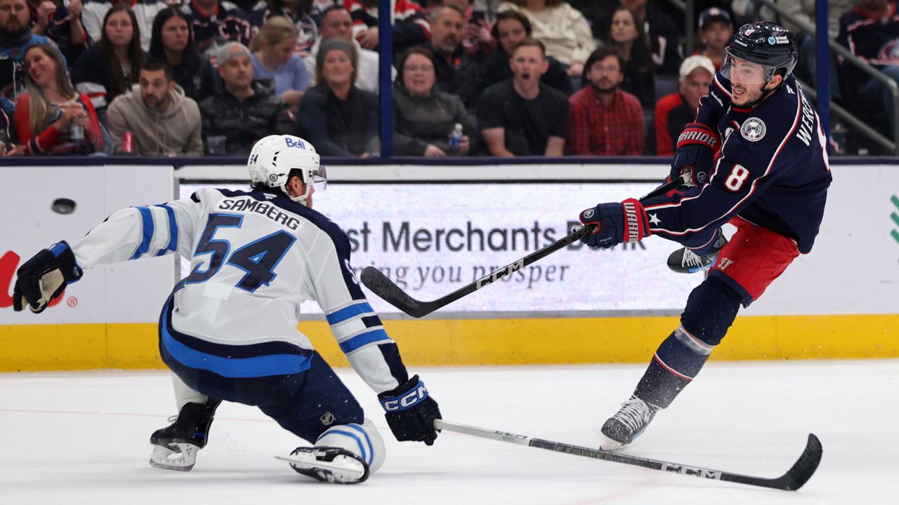 Columbus Blue Jackets defenseman Zach Werenski, right, shoots the puck in front of Winnipeg Jets defenseman Dylan Samberg during the second period of an NHL hockey game in Columbus, Ohio, Friday, Nov. 1, 2024.