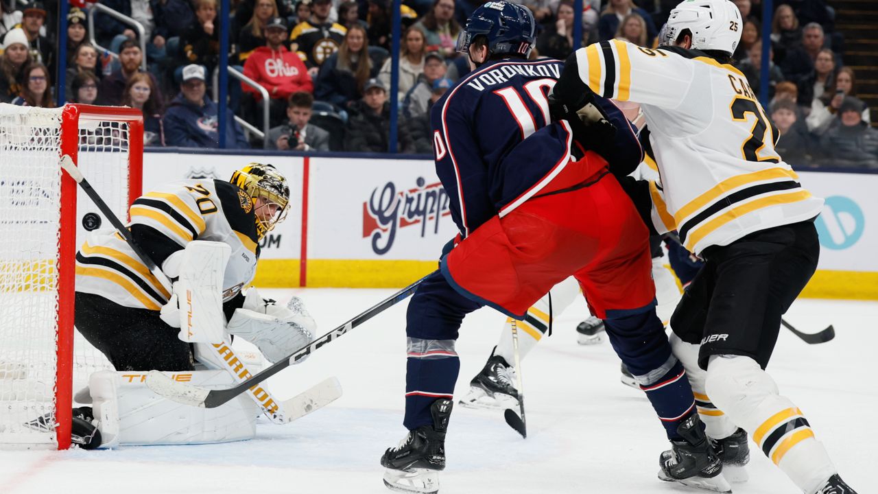 Columbus Blue Jackets' Dmitri Voronkov, center, scores against Boston Bruins' Joonas Korpisalo, left, as Brandon Carlo defends during the second period of an NHL hockey game Friday, Dec. 27, 2024, in Columbus, Ohio.