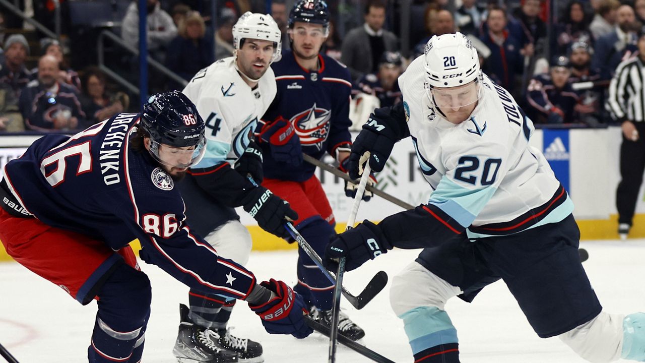 Seattle Kraken forward Eeli Tolvanen, right, shoots the puck in front of Columbus Blue Jackets forward Kirill Marchenko during the first period NHL hockey game in Columbus, Ohio, Saturday, Jan. 13, 2024. (AP Photo/Paul Vernon)