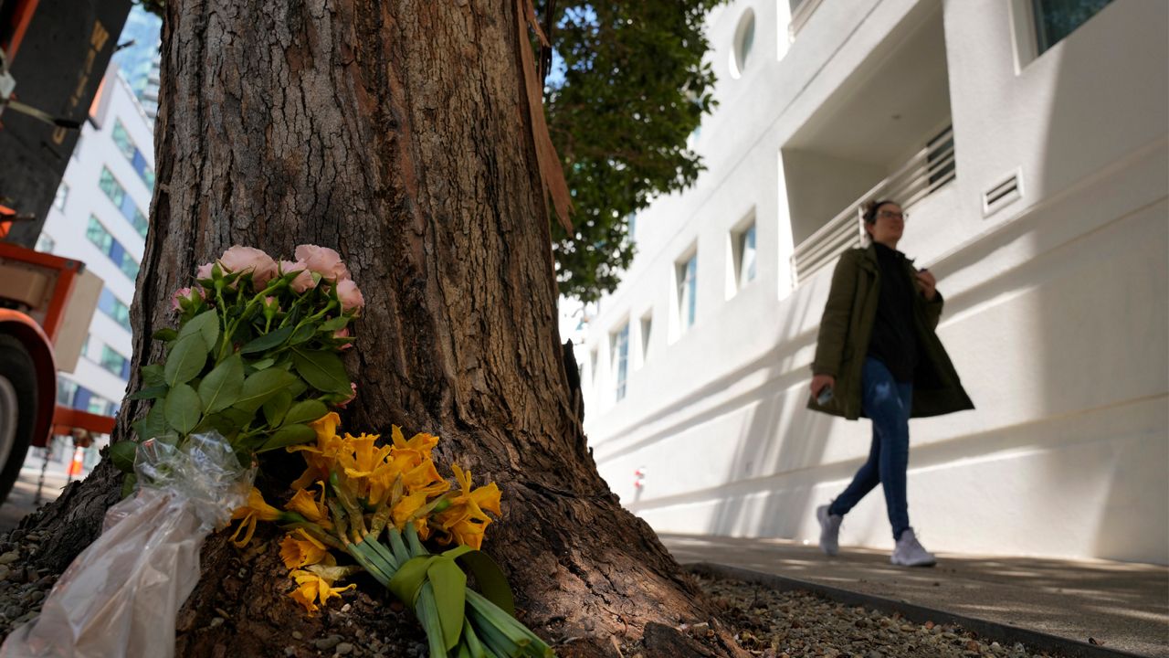 A woman walks past flowers left outside an apartment building where a technology executive was fatally stabbed in San Francisco on April 5, 2023. Bob Lee, a technology executive who created Cash App and was currently chief product officer of MobileCoin, was fatally stabbed in San Francisco early on April 4, 2023, according to the cryptocurrency platform and police. (AP Photo/Eric Risberg)