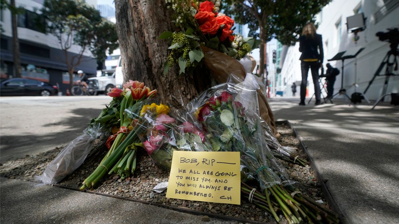 Flowers sit at a tree in front of the building where a technology executive was fatally stabbed outside of in San Francisco, Thursday, April 6, 2023. (AP Photo/Jeff Chiu)