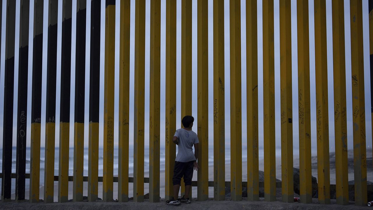 A boy looks through a border wall separating Mexico from the United States, Nov. 26, 2024, in Tijuana, Mexico. (AP Photo/Gregory Bull, File)