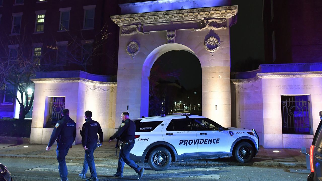 Law enforcement officials walk near an entrance to Brown University in Providence, R.I., on Saturday, Dec. 13, 2025, during the investigation of a shooting. (AP Photo/Steven Senne)