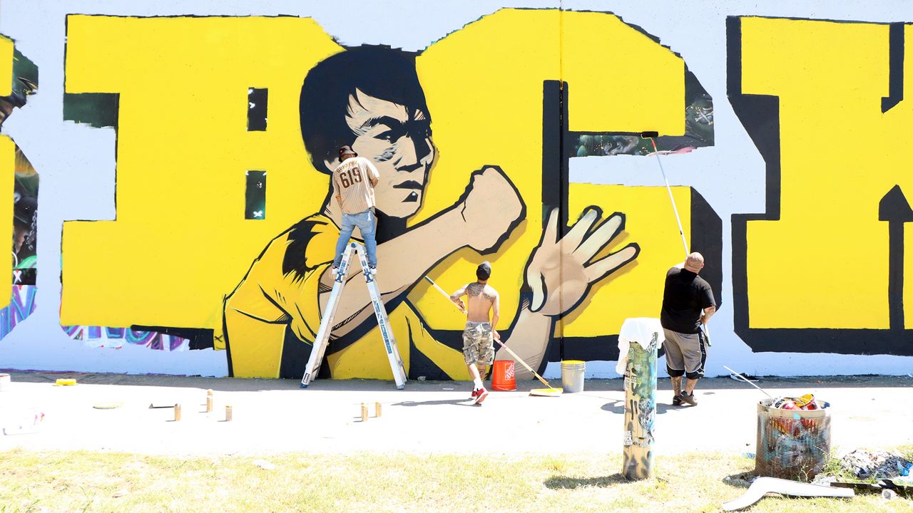 A group of graffiti artists from California collaborated on a Bruce Lee mural Friday, Sept. 1, on the flood wall, just south of the Arch, during the 26th annual Paint Louis. The event was held over the weekend where dozens of graffiti artists across the country came to Downtown St. Louis to create murals along the flood wall. (Spectrum News/Elizabeth Barmeier)