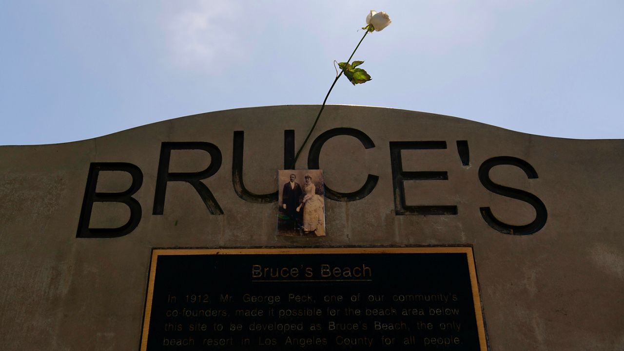 A rose is placed on a monument on Bruce's Beach in Manhattan Beach, Calif., Wednesday, July 20, 2022. Los Angeles County officials on Wednesday presented the deed to prime California oceanfront property to heirs of a Black couple who built a beach resort for African Americans but were harassed and finally stripped of the land nearly a century ago. The event marked the final step in a complex effort to address the long-ago wrong suffered by Charles and Willa Bruce, whose resort on the shore of the now-upscale city of Manhattan Beach was known as Bruce's Beach. (AP Photo/Jae C. Hong)