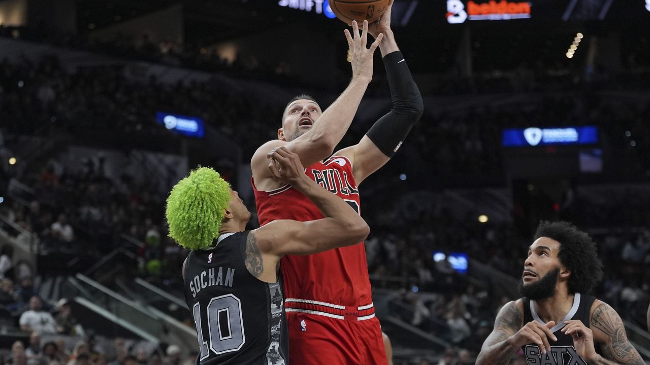 Chicago Bulls center Nikola Vucevic, center, looks to shoot over San Antonio Spurs forward Jeremy Sochan (10) during the second half of an NBA basketball game in San Antonio, Thursday, Dec. 5, 2024. (AP Photo/Eric Gay)