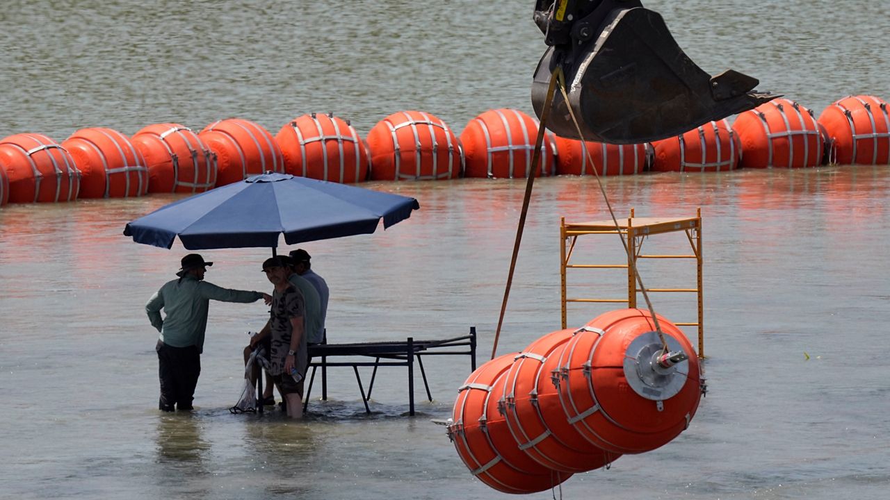 Workers take a break from deploying large buoys to be used as a border barrier along the banks of the Rio Grande in Eagle Pass, Texas, Wednesday, July 12, 2023. The floating barrier is being deployed in an effort to block migrants from entering Texas from Mexico. (AP Photo/Eric Gay)