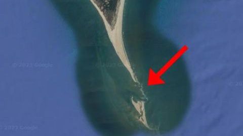 A satellite image of Cape Lookout shows a sandy beach coming to a sharp point, with a small island to the south. A red arrow indicates the area between the island and the point. (Google Maps via Cape Lookout National Seashore)