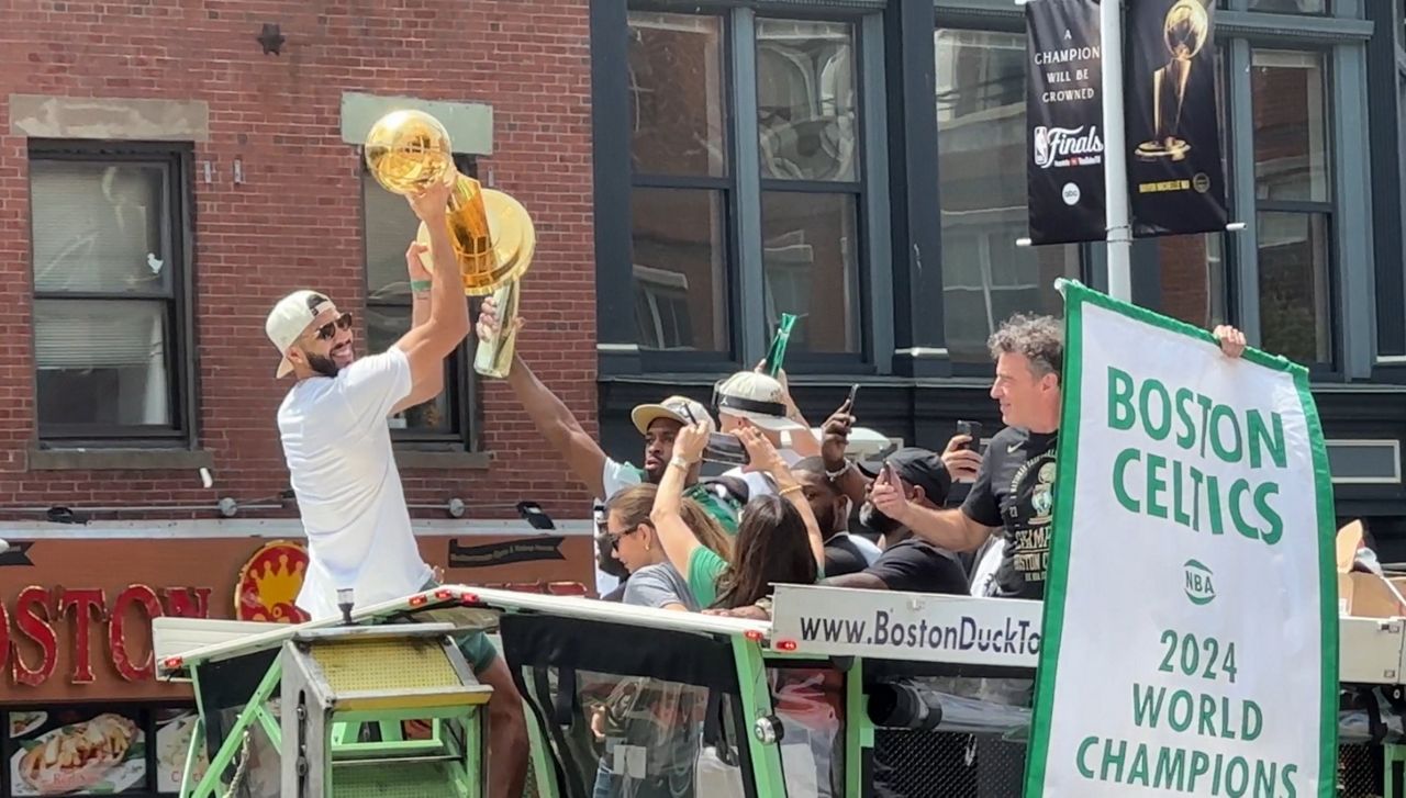 Jayson Tatum hoists the Larry O'Brien Championship trophy at Friday's parade. (Spectrum News 1/Cam Jandrow)