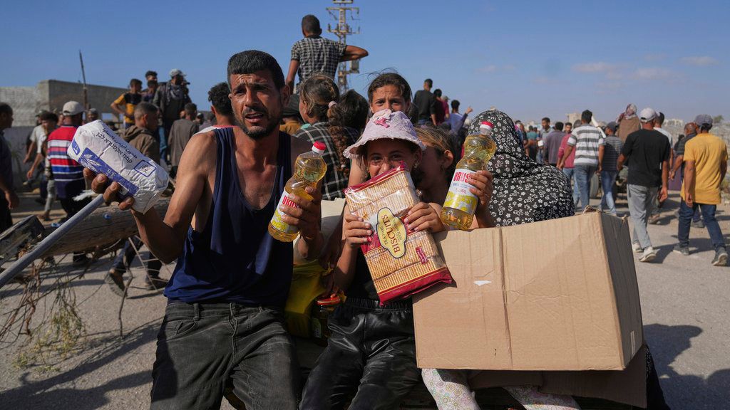 Palestinos muestran paquetes de comida que recibieron de la Fundación Humanitaria de Gaza, un grupo respaldado por EEUU y aprobado por Israel.