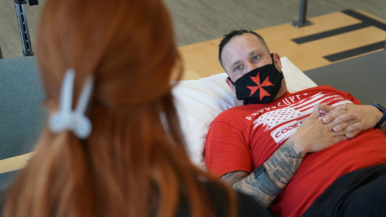 Patient Mike Camilleri works with physical therapist Beth Hughes in St. Louis, Mo., on March 1, 2023. Somehow, a mild case of COVID-19 set off a chain reaction that eventually left Camilleri with dangerous blood pressure spikes, a heartbeat that raced with slight exertion, and episodes of intense chest pain. (AP Photo/Angie Wang)