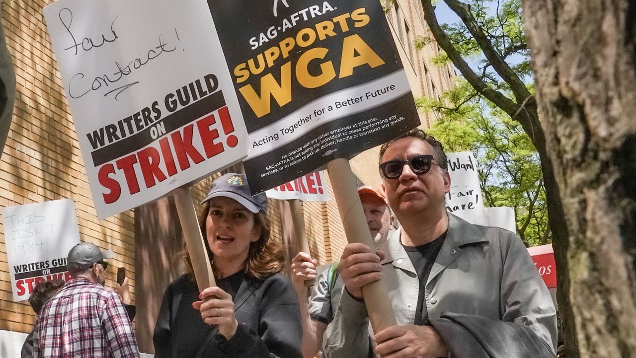 Actors and comedians Tina Fey, center, and Fred Armisen, right, join striking members of the Writers Guild of America on the picket line, during a rally outside Silvercup Studios, Tuesday May 9, 2023, in New York. (AP Photo/Bebeto Matthews)