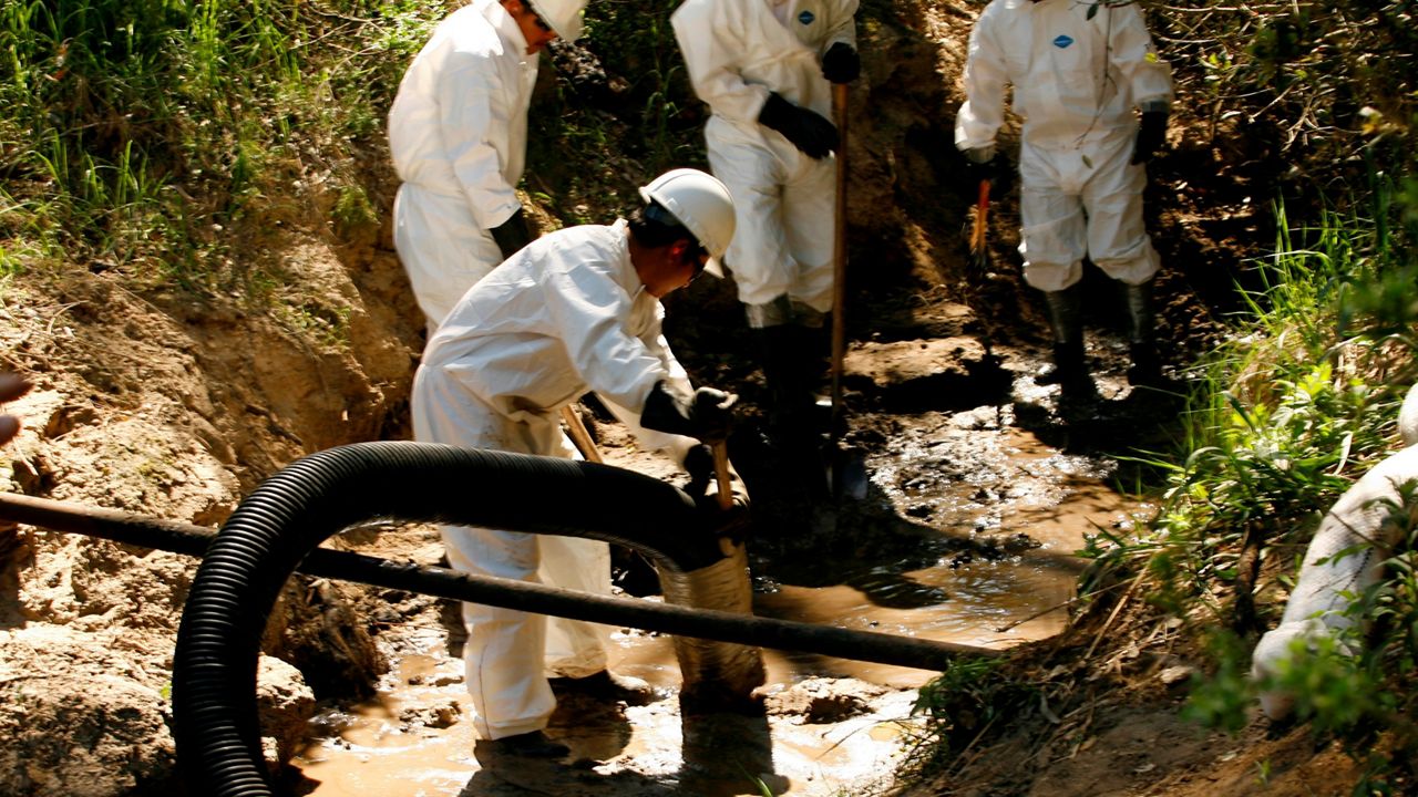 In this March 13, 2008, photo, workers use a guzzler vacuum to suck oil soaked sediment from a creek in Santa Maria, Calif., after oil spilled into the creek from a Greka Oil & Gas Inc. facility. (AP Photo/Damian Dovarganes, File)