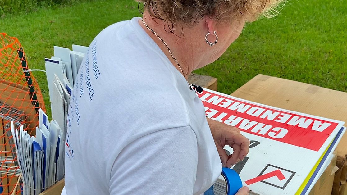 Kay Hudson, a volunteer with the League of Women Voters, tidies up a political sign drop-off site. (Spectrum News 13/Ashleigh Mills)