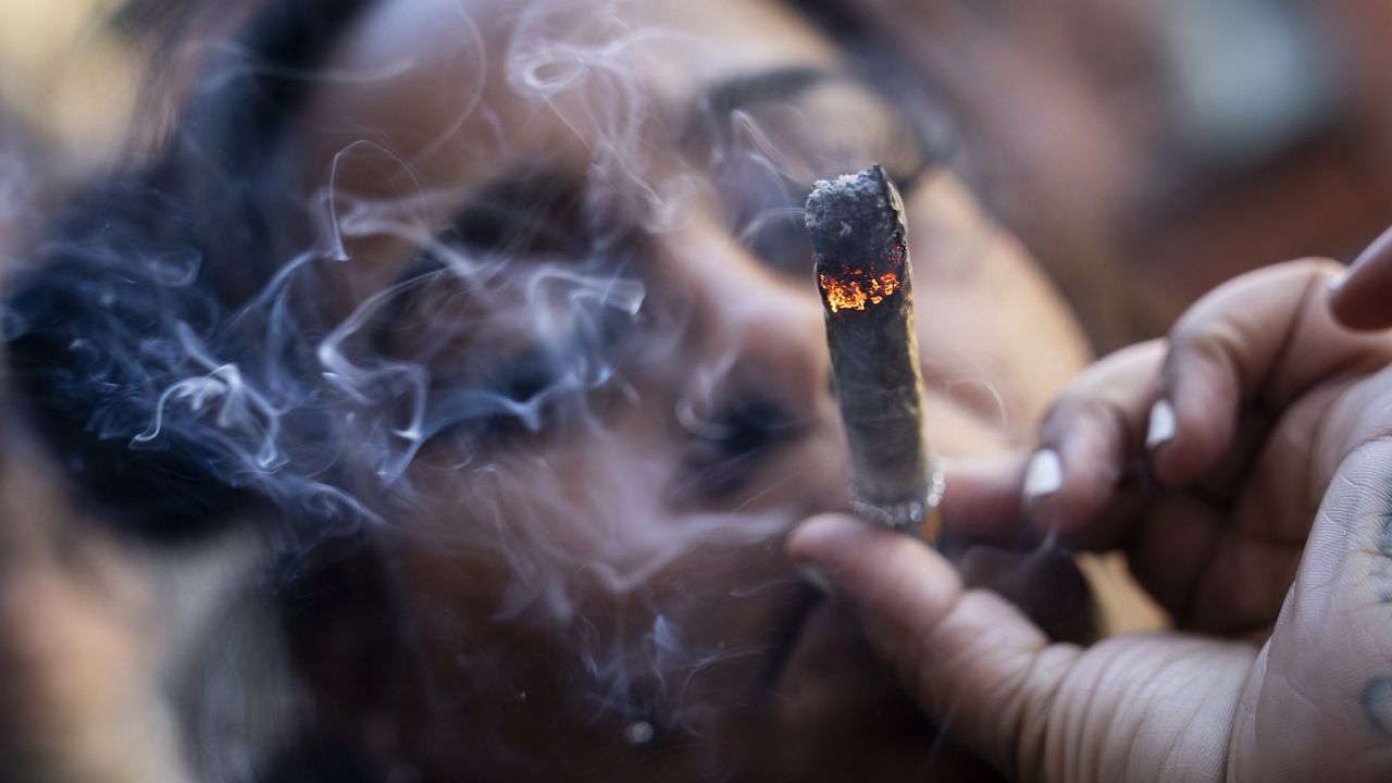 A person smokes cannabis outside the Smacked "pop up" cannabis dispensary location, Tuesday, Jan. 24, 2023, in New York. (AP Photo/John Minchillo, File)