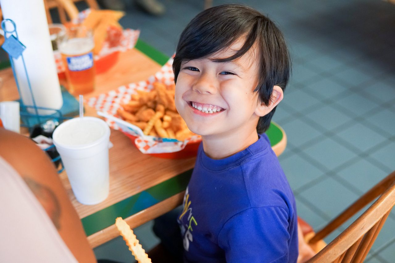A child grinning after receiving his meal.