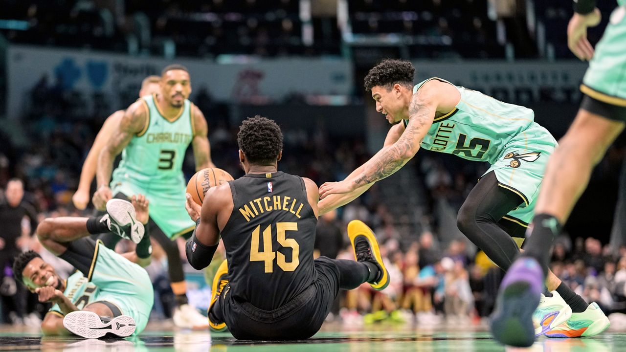 Cleveland Cavaliers guard Donovan Mitchell (45) and Charlotte Hornets guard KJ Simpson (25) battle for a loose ball during the first half of an NBA basketball game, Saturday, Dec. 7, 2024, in Charlotte, N.C.